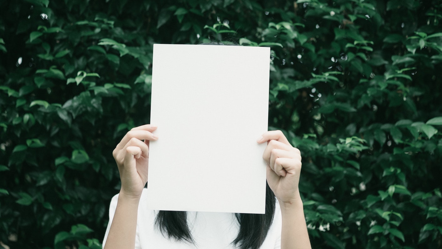 A person hiding their face with a paper